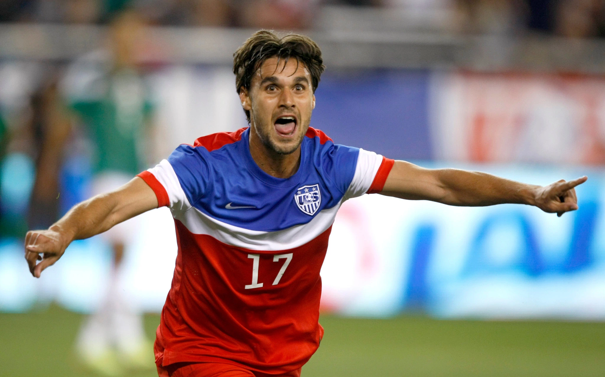 Chris Wondolowski in a U.S. soccer jersey celebrating on the field with arms outstretched